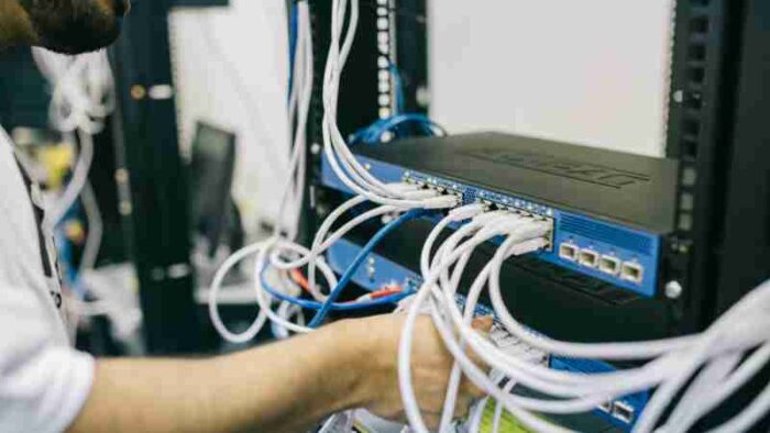 An IT professional configuring network cables in a server rack, focusing on Ethernet connections., tags: unternehmen - pexel