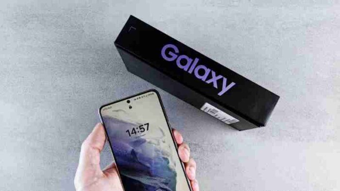 Close-up of a hand holding a smartphone with a Galaxy box on a neutral background., tags: samsung s26 ultra - pexel